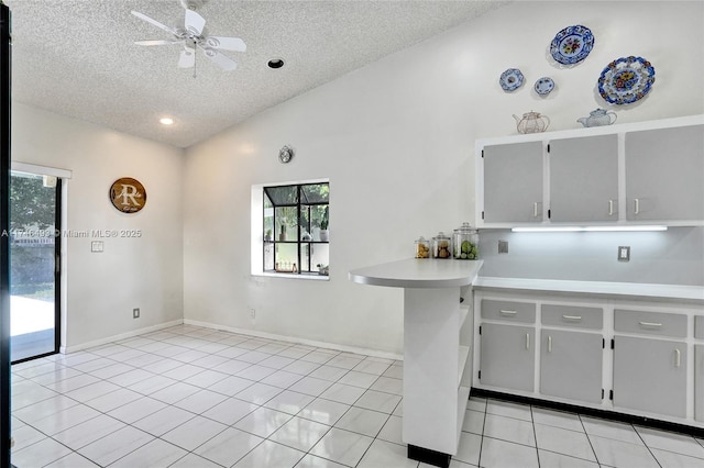 kitchen featuring lofted ceiling, ceiling fan, a textured ceiling, and light tile patterned flooring