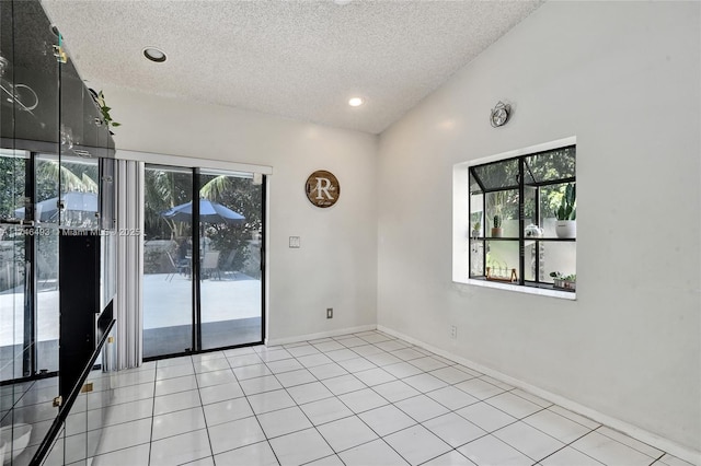 tiled spare room featuring vaulted ceiling and a textured ceiling