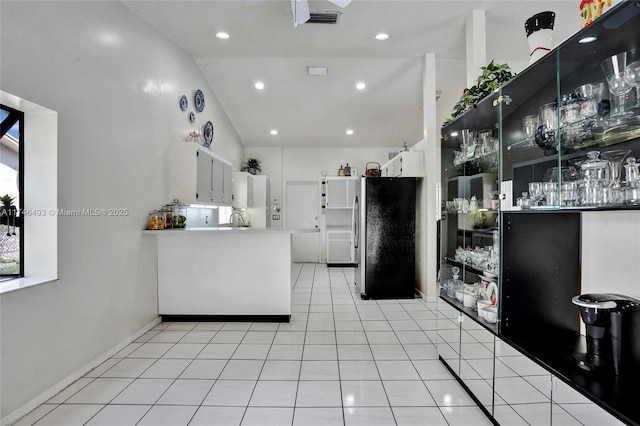 kitchen with white cabinetry, lofted ceiling, light tile patterned flooring, and stainless steel fridge