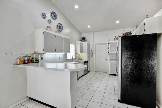 kitchen featuring light tile patterned flooring, lofted ceiling, sink, kitchen peninsula, and stainless steel appliances