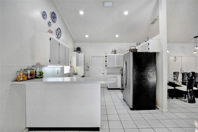 kitchen with light tile patterned flooring, stainless steel refrigerator, white cabinets, kitchen peninsula, and washer and clothes dryer