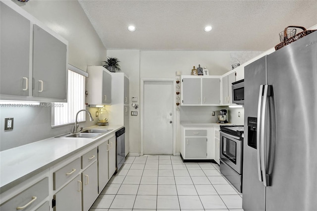 kitchen with sink, a textured ceiling, light tile patterned floors, appliances with stainless steel finishes, and white cabinets