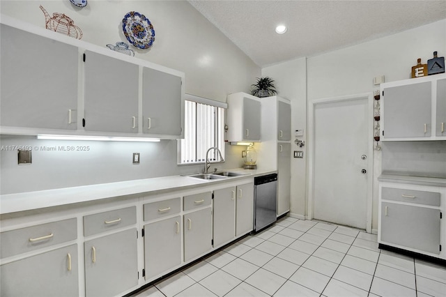 kitchen with sink, vaulted ceiling, a textured ceiling, light tile patterned floors, and dishwasher