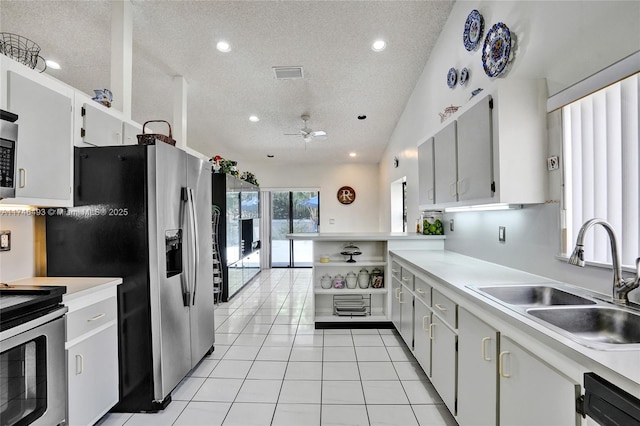 kitchen with sink, light tile patterned floors, appliances with stainless steel finishes, a textured ceiling, and white cabinets