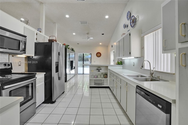 kitchen with sink, white cabinets, light tile patterned floors, ceiling fan, and stainless steel appliances