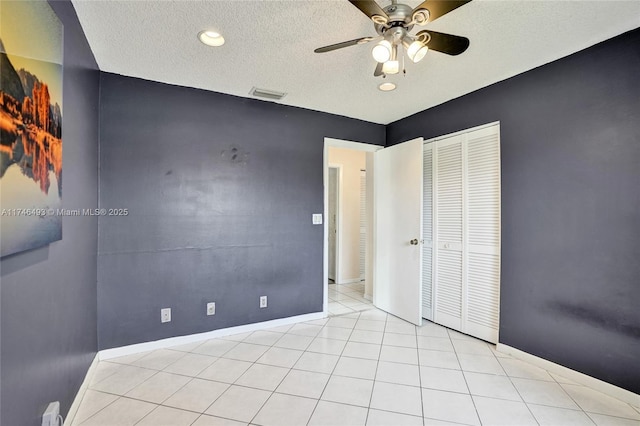 unfurnished bedroom featuring ceiling fan, a textured ceiling, a closet, and light tile patterned floors