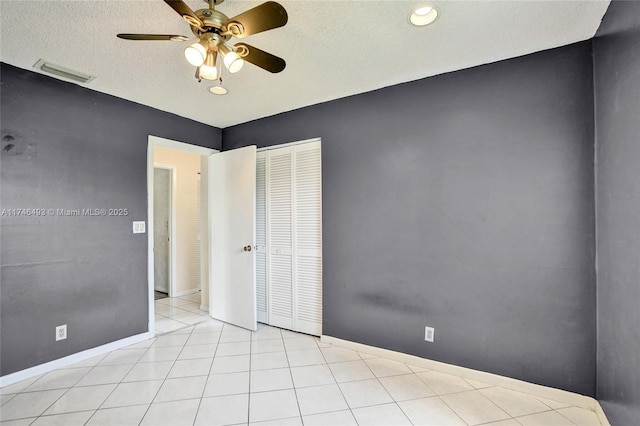 unfurnished bedroom featuring light tile patterned floors, a textured ceiling, ceiling fan, and a closet