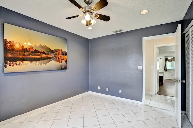 tiled empty room featuring a textured ceiling and ceiling fan