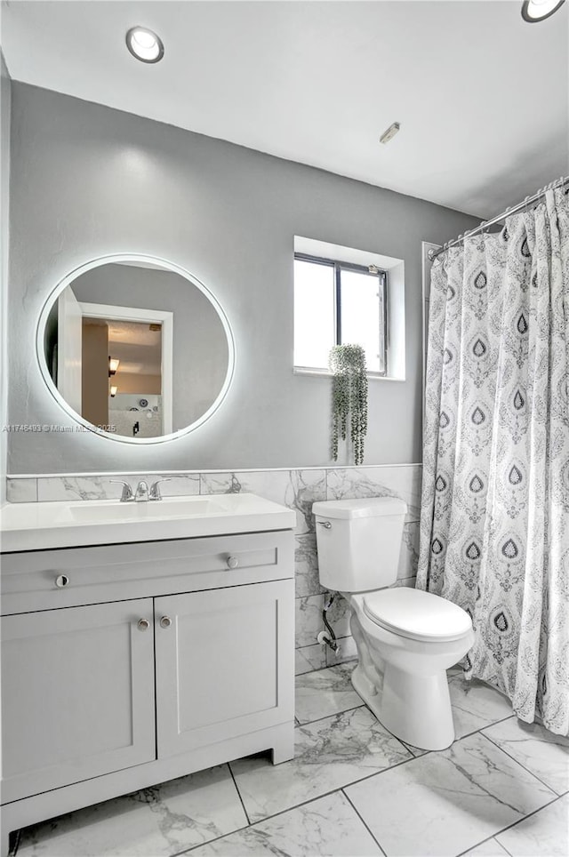 bathroom with vanity, toilet, and tile walls