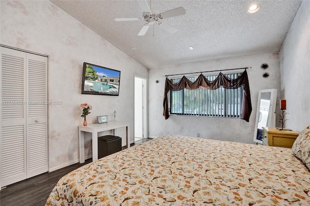 bedroom with dark wood-type flooring, vaulted ceiling, a textured ceiling, a closet, and ceiling fan