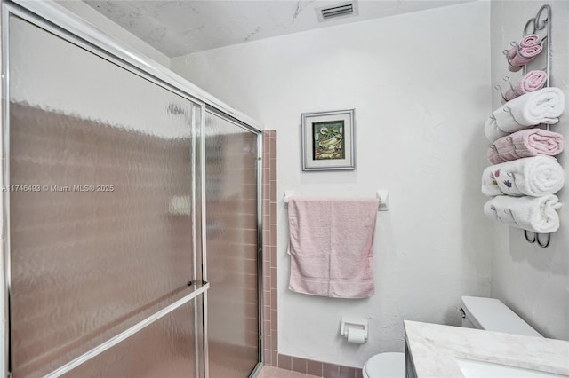 bathroom featuring vanity, a shower with door, and toilet