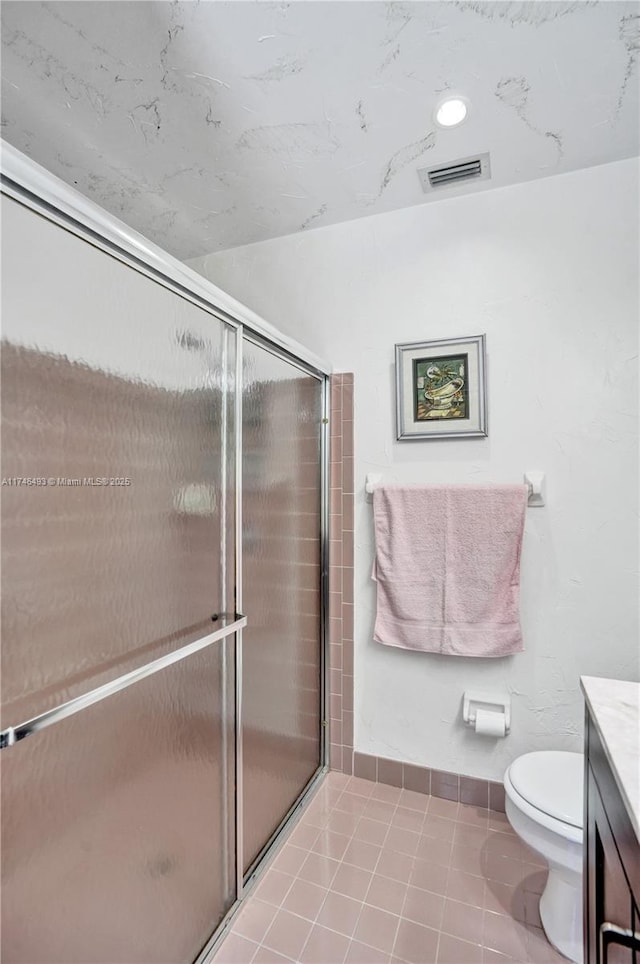 bathroom featuring a shower with door, vanity, tile patterned floors, and toilet