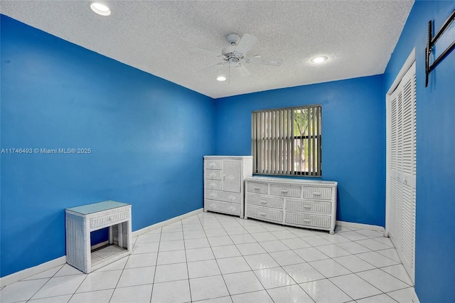 unfurnished bedroom featuring light tile patterned flooring, ceiling fan, a closet, and a textured ceiling