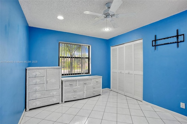 unfurnished bedroom featuring light tile patterned floors, a closet, a textured ceiling, and ceiling fan