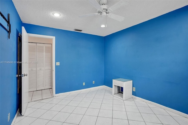 tiled empty room featuring ceiling fan and a textured ceiling