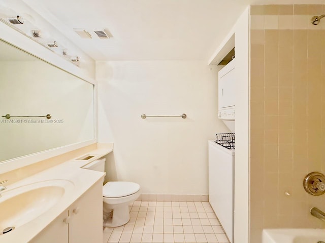 full bathroom featuring stacked washer and dryer, vanity, tiled shower / bath combo, tile patterned flooring, and toilet