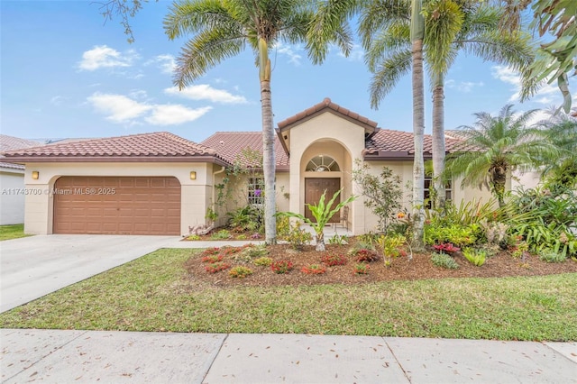 mediterranean / spanish home with driveway, a tiled roof, an attached garage, a front yard, and stucco siding