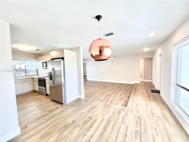 kitchen featuring hanging light fixtures, appliances with stainless steel finishes, and light hardwood / wood-style floors