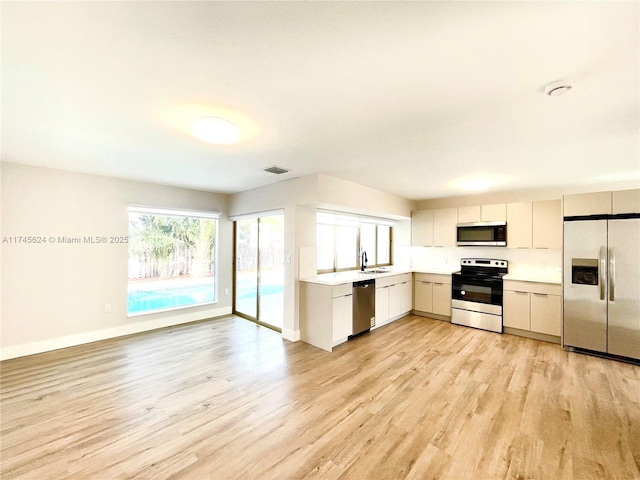 kitchen featuring sink, stainless steel appliances, light hardwood / wood-style floors, and white cabinets