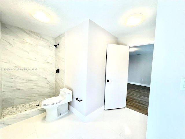 bathroom with tiled shower, tile patterned floors, and toilet