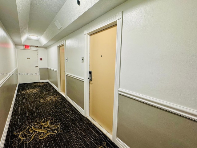 hallway featuring carpet flooring and a textured ceiling