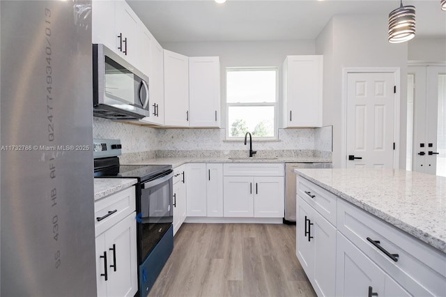 kitchen featuring appliances with stainless steel finishes, pendant lighting, white cabinetry, sink, and light stone counters