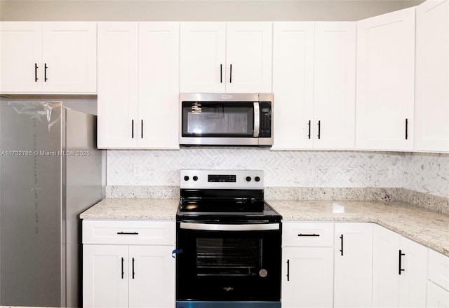 kitchen featuring white cabinetry, decorative backsplash, appliances with stainless steel finishes, and light stone counters