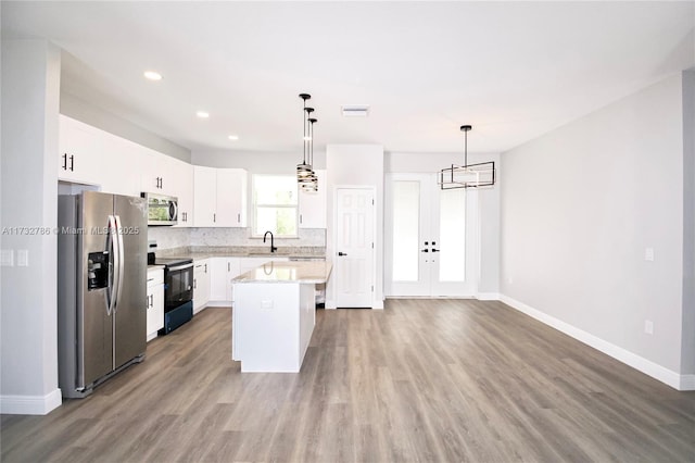 kitchen with sink, white cabinetry, a center island, appliances with stainless steel finishes, and pendant lighting