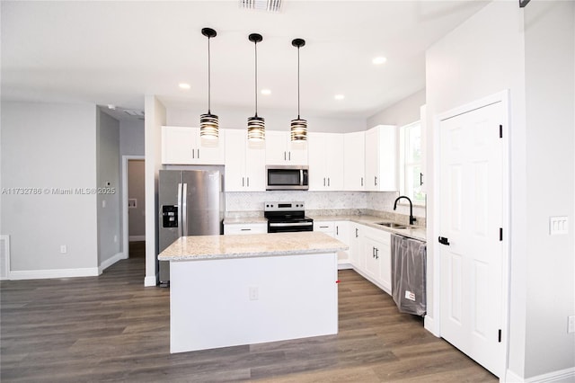 kitchen featuring white cabinetry, a center island, pendant lighting, stainless steel appliances, and light stone countertops