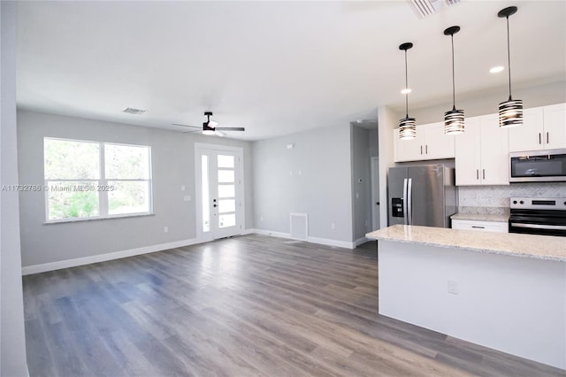 kitchen featuring white cabinetry, decorative light fixtures, stainless steel appliances, light stone countertops, and decorative backsplash