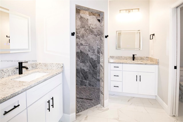 bathroom with vanity, toilet, and tiled shower