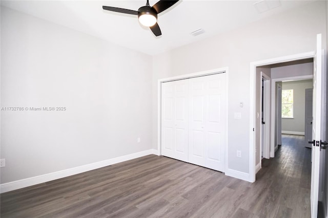 unfurnished bedroom featuring ceiling fan, dark hardwood / wood-style flooring, and a closet