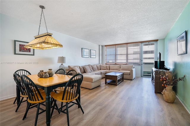 dining room featuring wood-type flooring and a textured ceiling