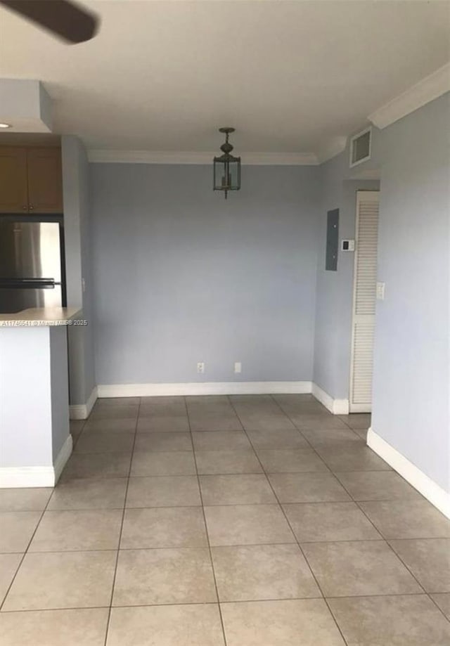 unfurnished dining area with baseboards, visible vents, crown molding, and tile patterned floors