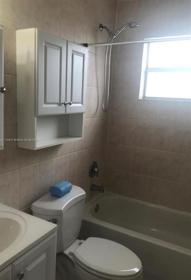 bathroom featuring toilet, shower / washtub combination, tile walls, and vanity