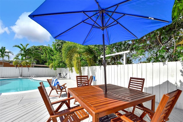 view of pool featuring fence, outdoor dining area, a fenced in pool, and a wooden deck