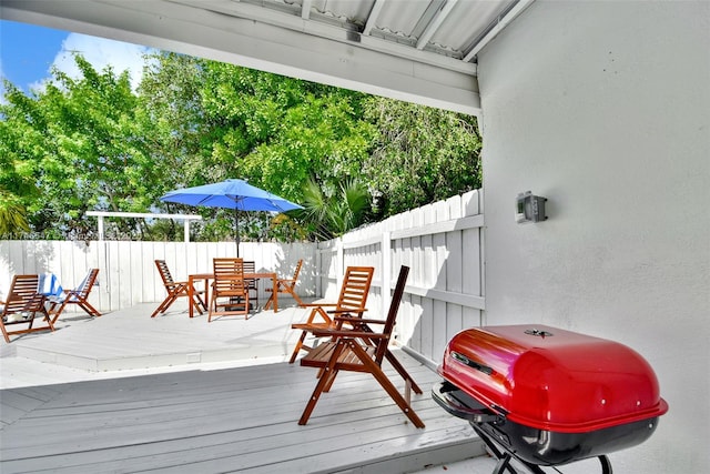 deck featuring outdoor dining area, a grill, and a fenced backyard