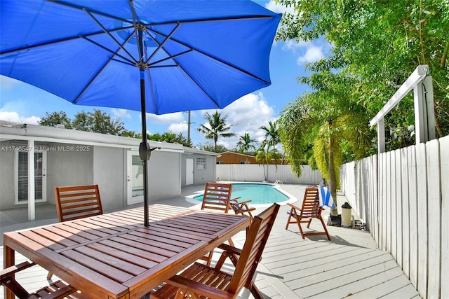 wooden terrace with a fenced backyard, a fenced in pool, and outdoor dining space