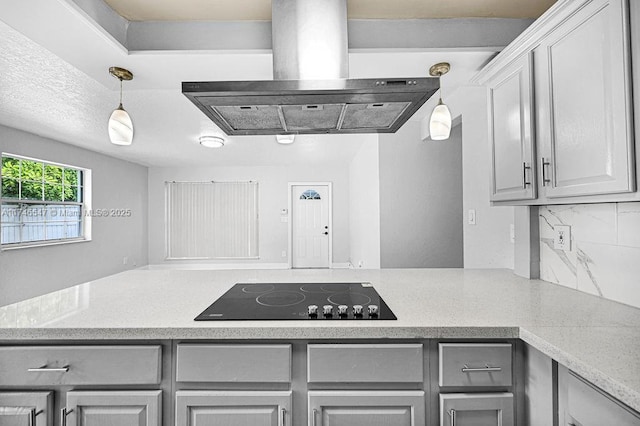 kitchen featuring black electric cooktop, island range hood, hanging light fixtures, backsplash, and gray cabinets