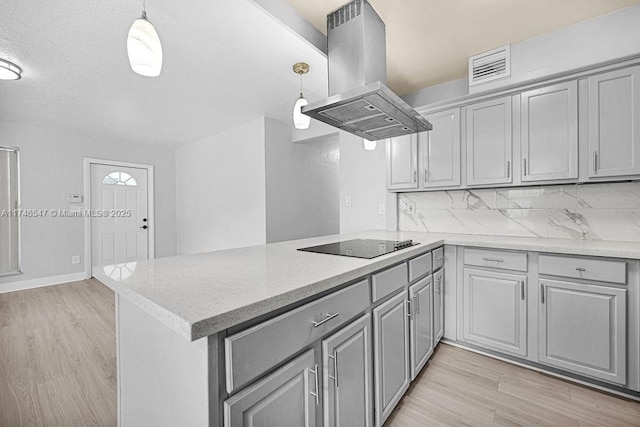 kitchen featuring island exhaust hood, gray cabinets, light wood-type flooring, a peninsula, and black electric cooktop