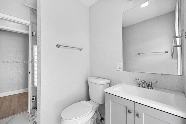 full bathroom featuring toilet, a shower stall, vanity, and a textured wall