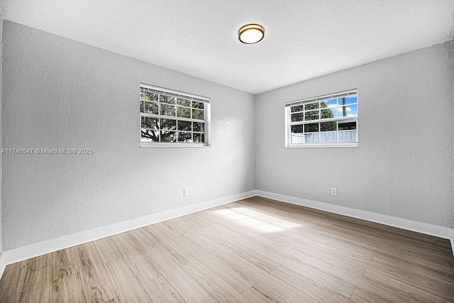 unfurnished room featuring a textured ceiling, baseboards, wood finished floors, and a textured wall