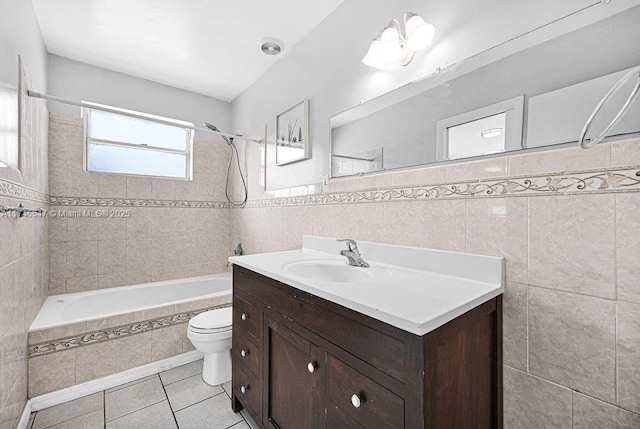 full bath with tile patterned flooring, toilet, tiled shower / bath combo, vanity, and tile walls