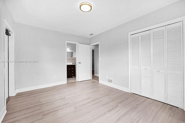 unfurnished bedroom with light wood finished floors, visible vents, baseboards, and a closet