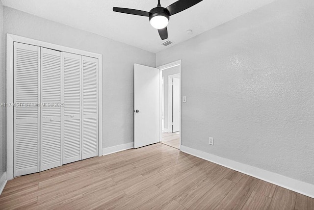 unfurnished bedroom featuring a closet, visible vents, ceiling fan, light wood-type flooring, and baseboards