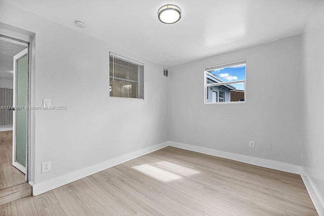 empty room featuring wood finished floors, visible vents, and baseboards