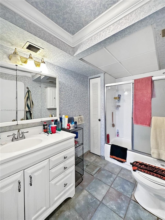 bathroom featuring toilet, vanity, visible vents, combined bath / shower with glass door, and wallpapered walls