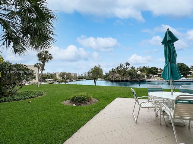 view of home's community with a water view, a lawn, and a patio