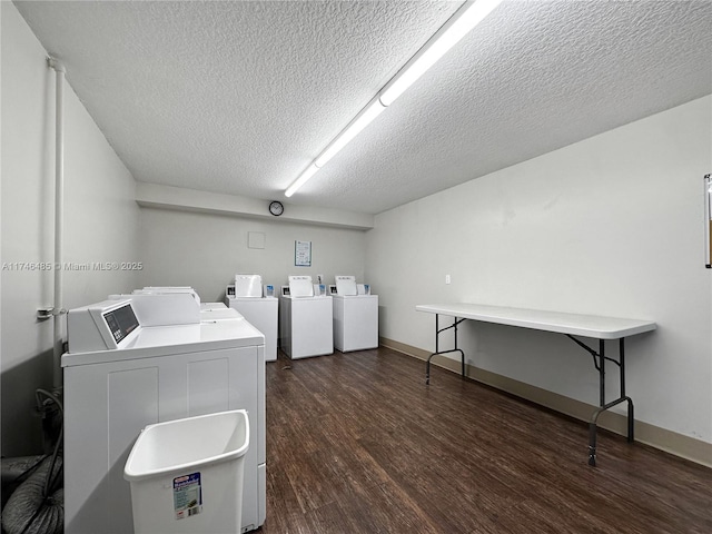 common laundry area featuring a textured ceiling, washing machine and dryer, dark wood finished floors, and baseboards