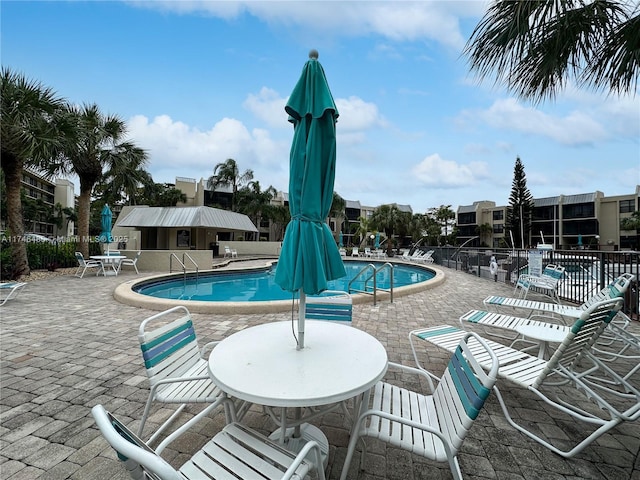 community pool with a patio area and fence